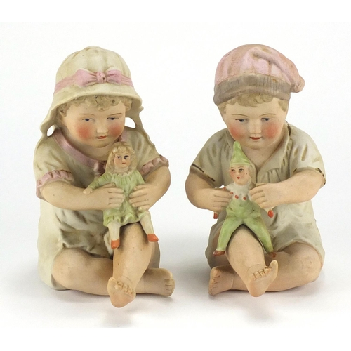 74 - Pair of bisque babies holding dolls, the largest 16cm high