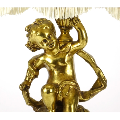 2176 - Gilt brass putti design table lamp, with silk lined tasselled shade, 67cm high