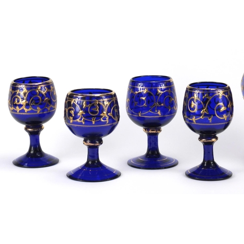 2390 - Venetian blue glass jug and four glasses, each gilded with foliate scrolls, the carafe 28cm high