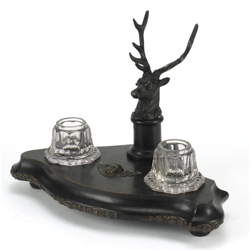 2201 - Ebonised stags head design desk stand, fitted with a pair of glass inkwells, 27cm wide