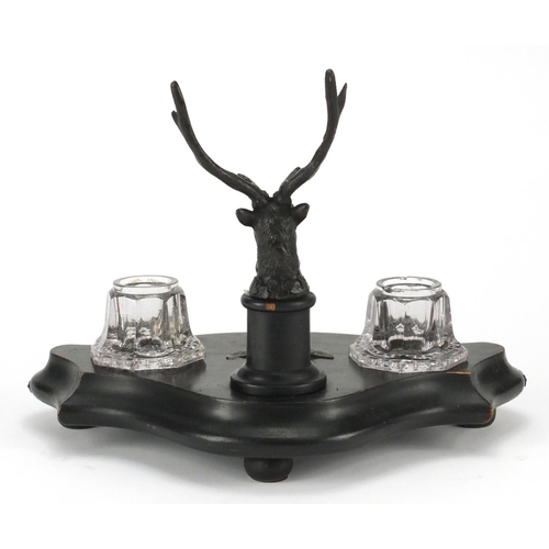 2201 - Ebonised stags head design desk stand, fitted with a pair of glass inkwells, 27cm wide