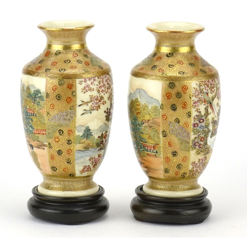 313 - Pair of Japanese Satsuma pottery vases raised on hardwood stands, hand painted with figures, flowers... 