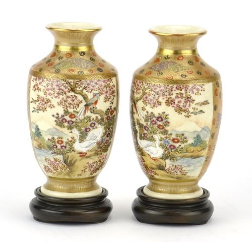 313 - Pair of Japanese Satsuma pottery vases raised on hardwood stands, hand painted with figures, flowers... 