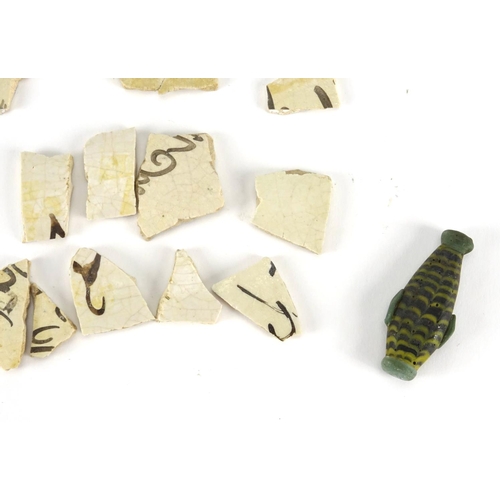 389 - Group of antique Islamic pottery fragments and a glass scent bottle, the scent bottle 4.6cm high
