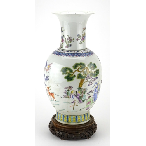 297 - Chinese porcelain baluster vase raised on a hardwood stand, finely hand painted in the famille rose ... 