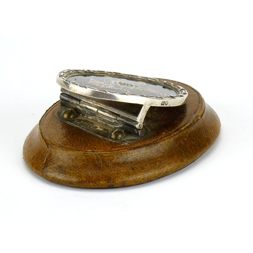 587 - Silver and tortoiseshell pique work letter clip, mounted on a brown leather base, by William Comyns ... 