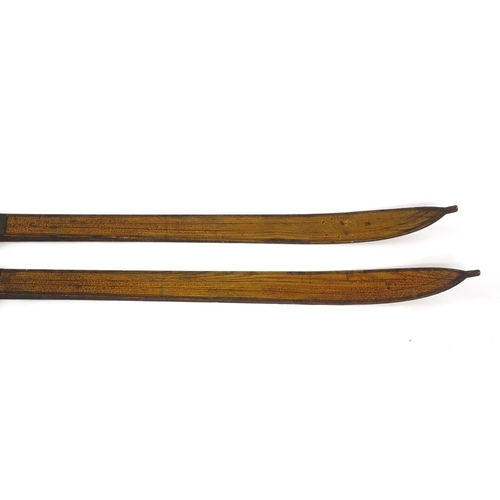 423 - Pair of wooden ski's with leather mounts with incised decoration, possibly Norwegian, each 220cm in ... 