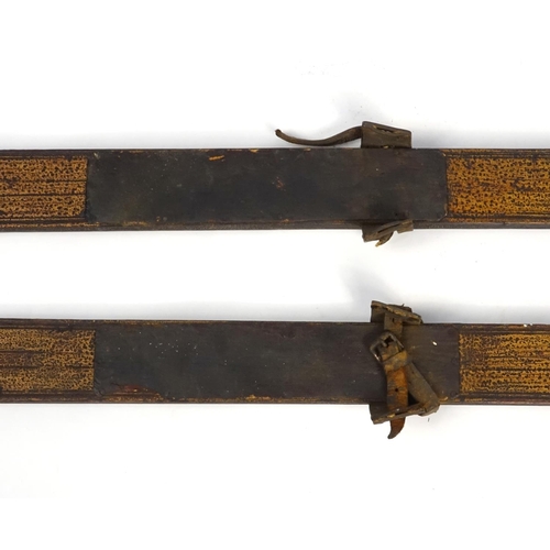 423 - Pair of wooden ski's with leather mounts with incised decoration, possibly Norwegian, each 220cm in ... 