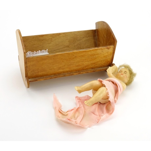 2549 - Wax baby doll with rocking crib, the doll 17cm in length