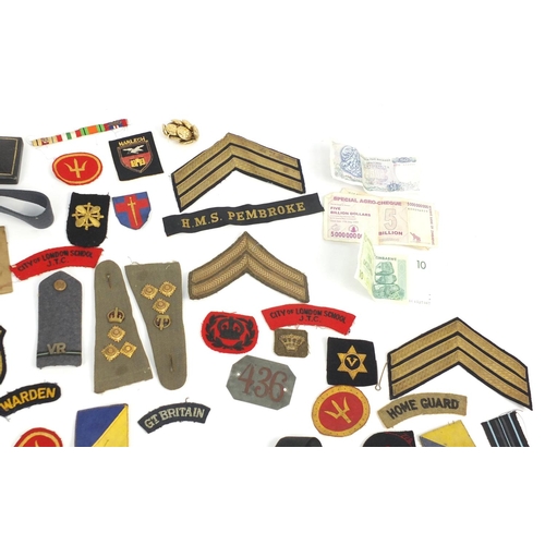 790 - Militaria including cloth patches, cap badges, pips and cap tallies