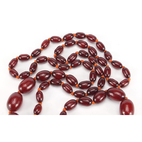 766 - Cherry amber coloured graduated bead necklace, the largest bead approximately 2.7cm wide, 96cm in le... 