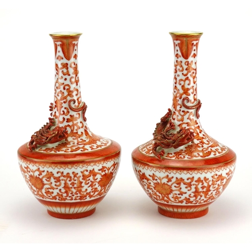 302 - Pair of Chinese porcelain vases decorated in relief with dragons, each hand painted in iron red with... 