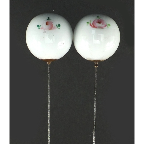 342 - Pair of Japanese porcelain hat pins, hand painted with flowers, each 23.5cm in length