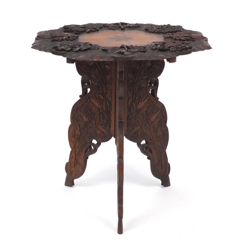 2065 - Anglo-Indian table on folding tripod base, profusely carved with fruiting vines, 61cm high x 63cm in... 