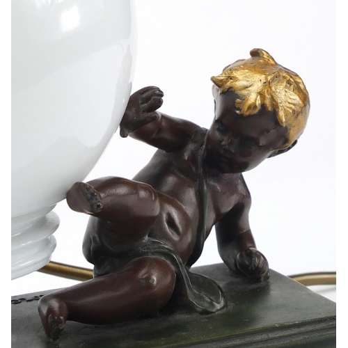 2322 - After Moreau - Bronzed putti table lamp with globular glass shade, 23.5cm high