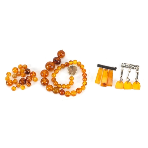 2852 - Amber coloured bead necklace, two brooches and loose beads, approximate weight 38.6g