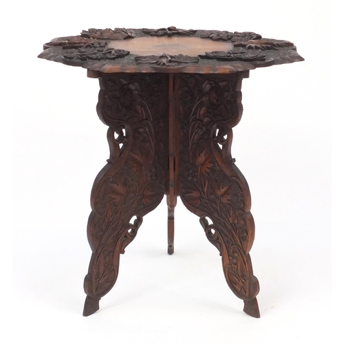2018 - Anglo-Indian table on folding tripod base, profusely carved with fruiting vines, 61cm high x 63cm in... 