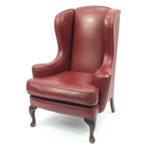 2016 - Burgundy leather wingback armchair raised on cabriole feet, 116cm high