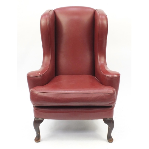 2016 - Burgundy leather wingback armchair raised on cabriole feet, 116cm high