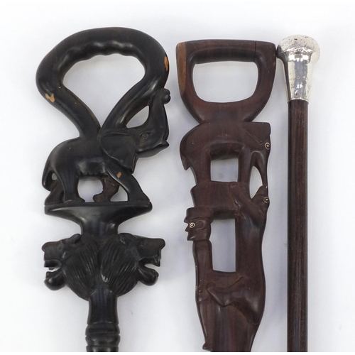 713 - Two African carved walking sticks and one with silver pommel, the largest 91cm in length