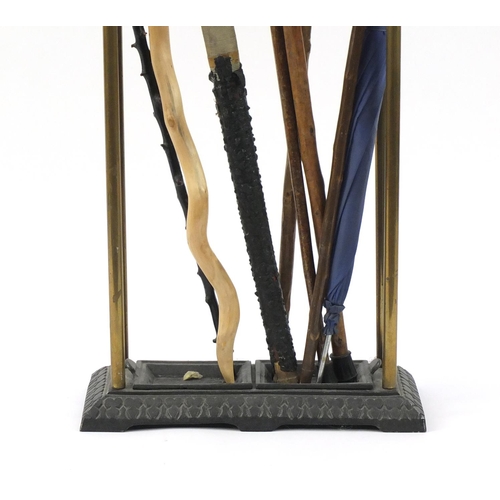 62 - Victorian brass and cast iron stick stand with a selection of walking sticks