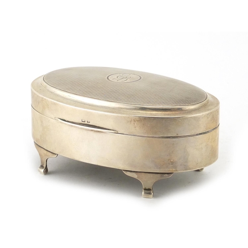 852 - Oval silver jewel box raised on four feet, the hinged lid with engine turned decoration, retailed by... 