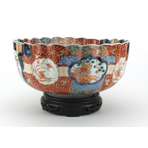 501 - Large Japanese Imari fluted bowl raised on a hardwood stand, hand painted with roundels, birds of pa... 