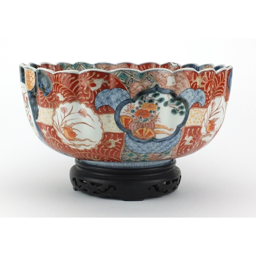 501 - Large Japanese Imari fluted bowl raised on a hardwood stand, hand painted with roundels, birds of pa... 