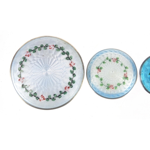 811 - Four silver and guilloche enamel circular brooches hand painted with roses, the largest 5cm in diame... 