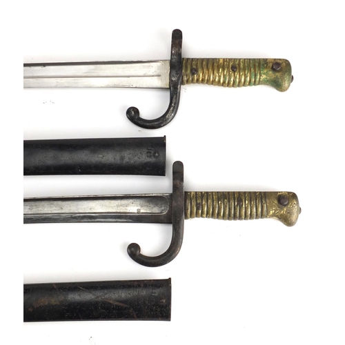 370 - Two French Military interest long bayonets with scabbards, both with impressed marks, each 71cm in l... 