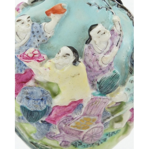 417 - Chinese porcelain relief snuff bottle raised on a carved hardwood stand, hand painted in the famille... 