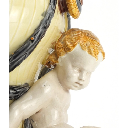 698 - Victorian Majolica centrepiece by Wedgewood modelled as an urn supported by two putti, raised over a... 