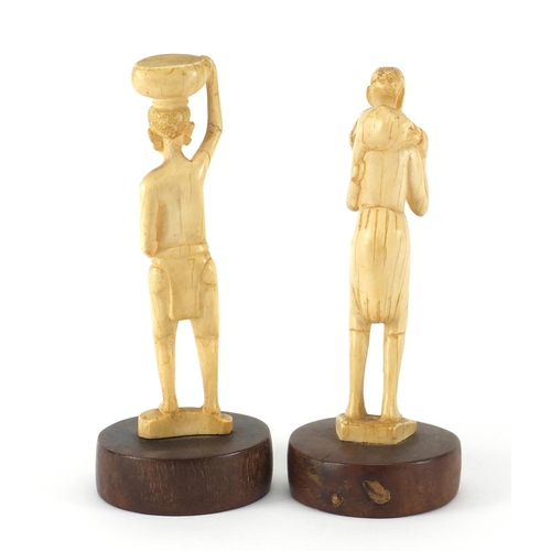 646 - Pair of African ivory carvings of tribes people, raised on circular hardwood bases, the largest 22cm... 