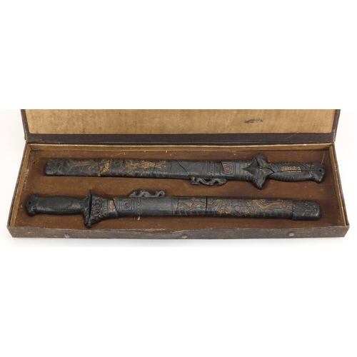 578 - Two Chinese gilt decorated black ink stone swords, housed in a fitted case with calligraphy, each 43... 