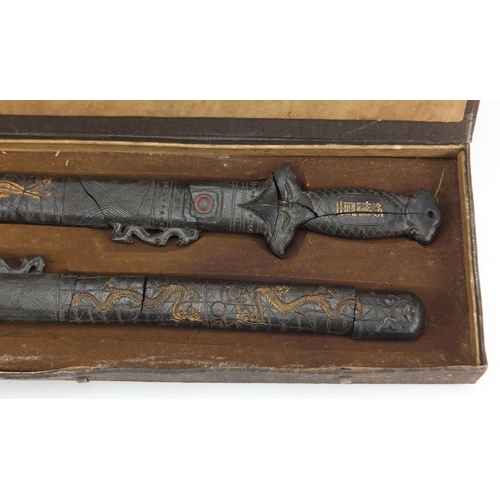 578 - Two Chinese gilt decorated black ink stone swords, housed in a fitted case with calligraphy, each 43... 