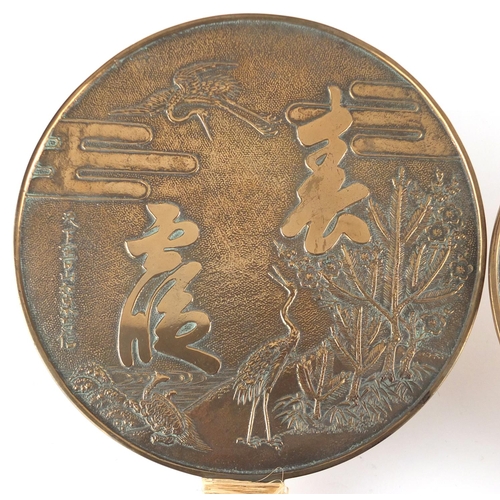 571 - Two Japanese bronze hand mirrors cast with cranes, flowers and script, the largest  32cm in length