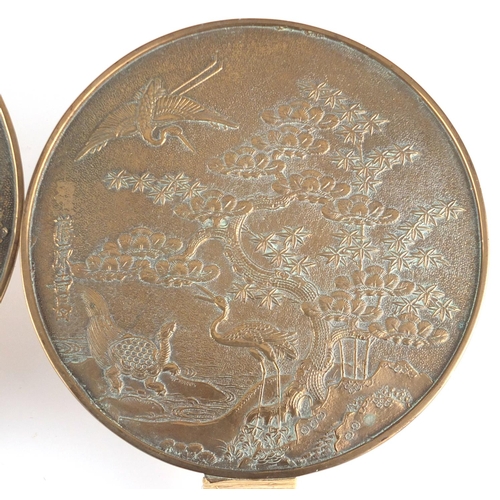 571 - Two Japanese bronze hand mirrors cast with cranes, flowers and script, the largest  32cm in length