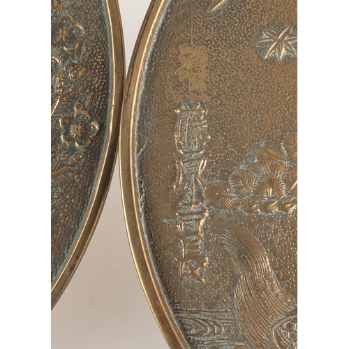 571 - Two Japanese bronze hand mirrors cast with cranes, flowers and script, the largest  32cm in length