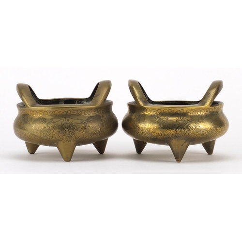 562 - Pair of Chinese bronze tripod incense burners with twin handles, each engraved with dragons amongst ... 