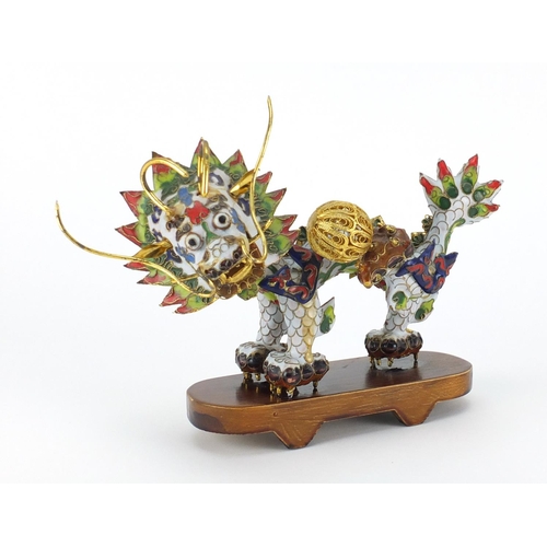 554 - Chinese gilt metal and enamel dragon raised on hardwood stand, 22.5cm in length