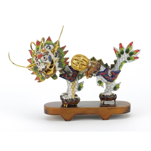 554 - Chinese gilt metal and enamel dragon raised on hardwood stand, 22.5cm in length