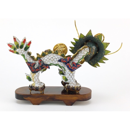 554 - Chinese gilt metal and enamel dragon raised on hardwood stand, 22.5cm in length