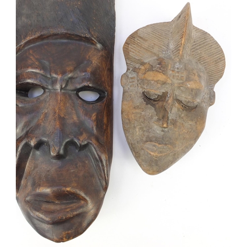 665 - African tribal carvings including two face masks and a fertility figure, the largest 62cm in length