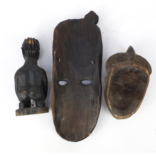 665 - African tribal carvings including two face masks and a fertility figure, the largest 62cm in length