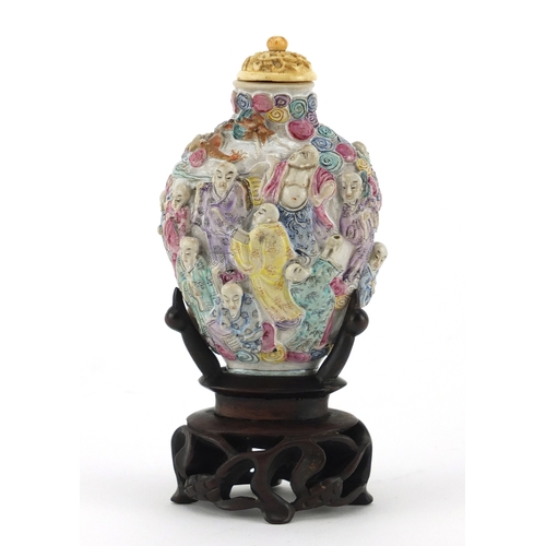 395 - Good Chinese porcelain relief snuff bottle with ivory stopper, raised on a carved hardwood stand, ha... 