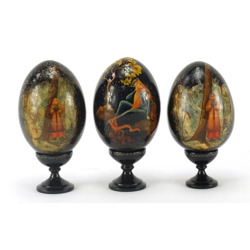 2823 - Three Russian papier-mâché eggs on stands, each hand painted with figures and with inscriptions to t... 