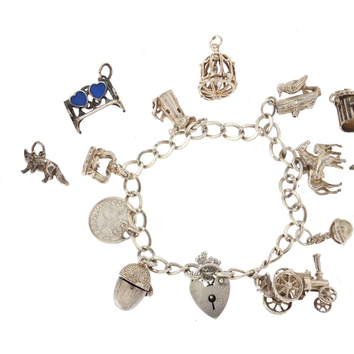 2918 - Two silver charm bracelets with a selection of mostly silver charms, including steam tractor, horse ... 