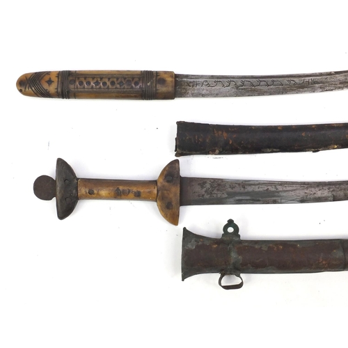 921 - Two tribal bone handled daggers with sheaths, the largest 50cm in length