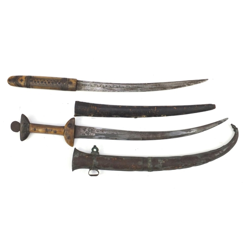 921 - Two tribal bone handled daggers with sheaths, the largest 50cm in length