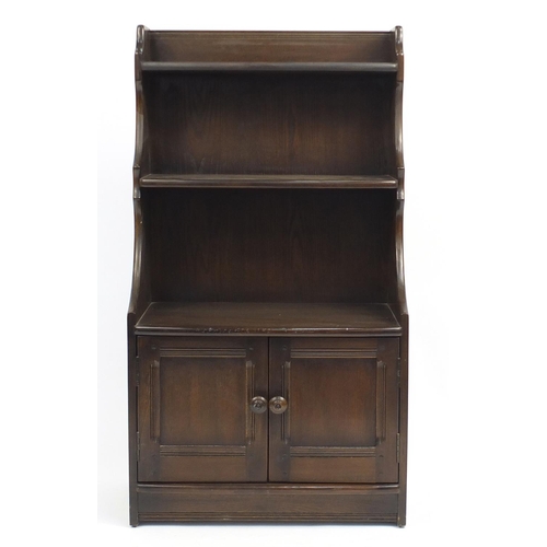 45 - Ercol elm waterfall bookcase, fitted with a pair of cupboard doors to the base, 111cm H x 61cm W x 3... 